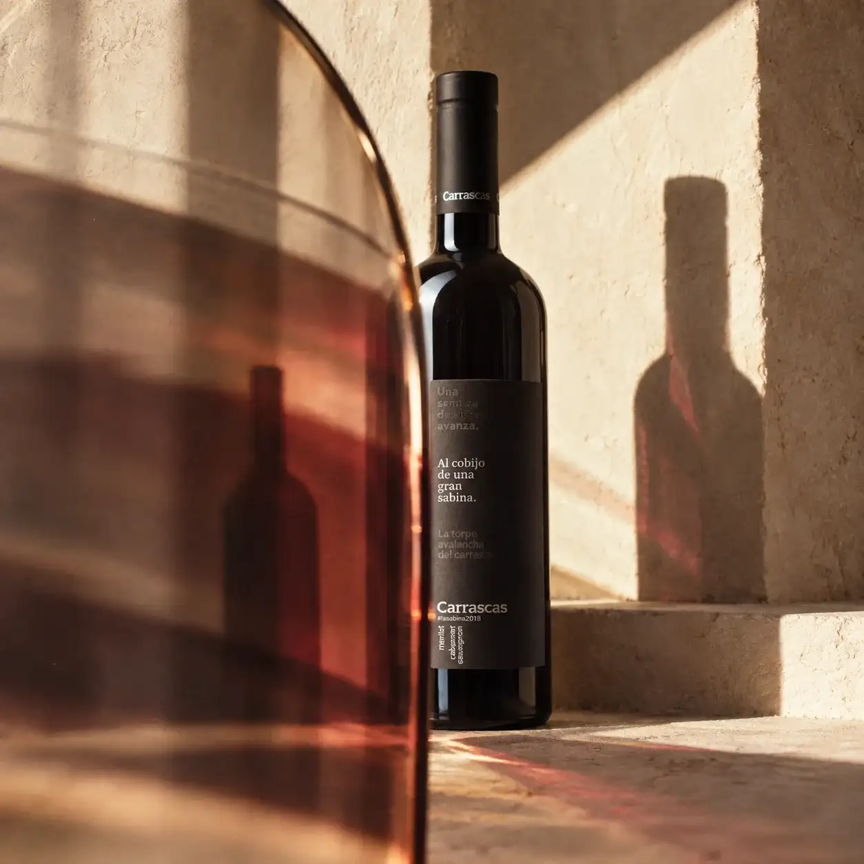 Botella de vino Carrascas sobre un escalón de piedra, con su sombra y la luz cálida de la tarde.