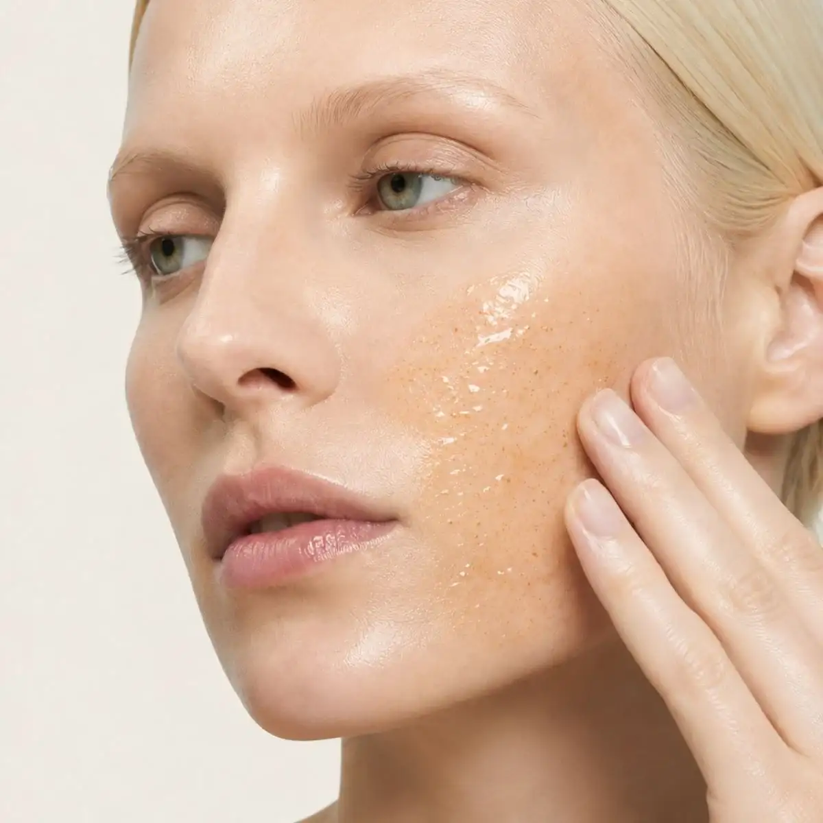 Modelo aplicándose el exfoliante Dermo Peel en la mejilla, sobre fondo claro.