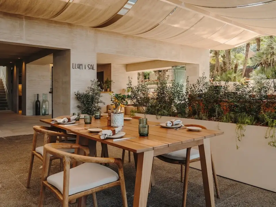 Terraza de Llum i Sal con mesas de madera bajo un toldo y el nombre del restaurante en la pared.