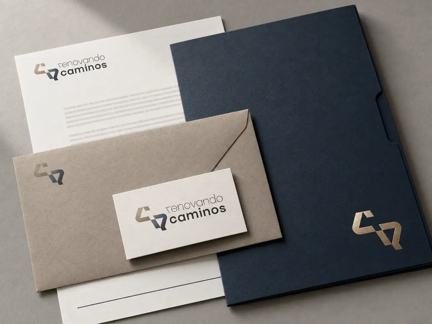 Papelería de Renovando Caminos: carta, sobre, tarjeta y carpeta azul noche con el símbolo estampado en oro.