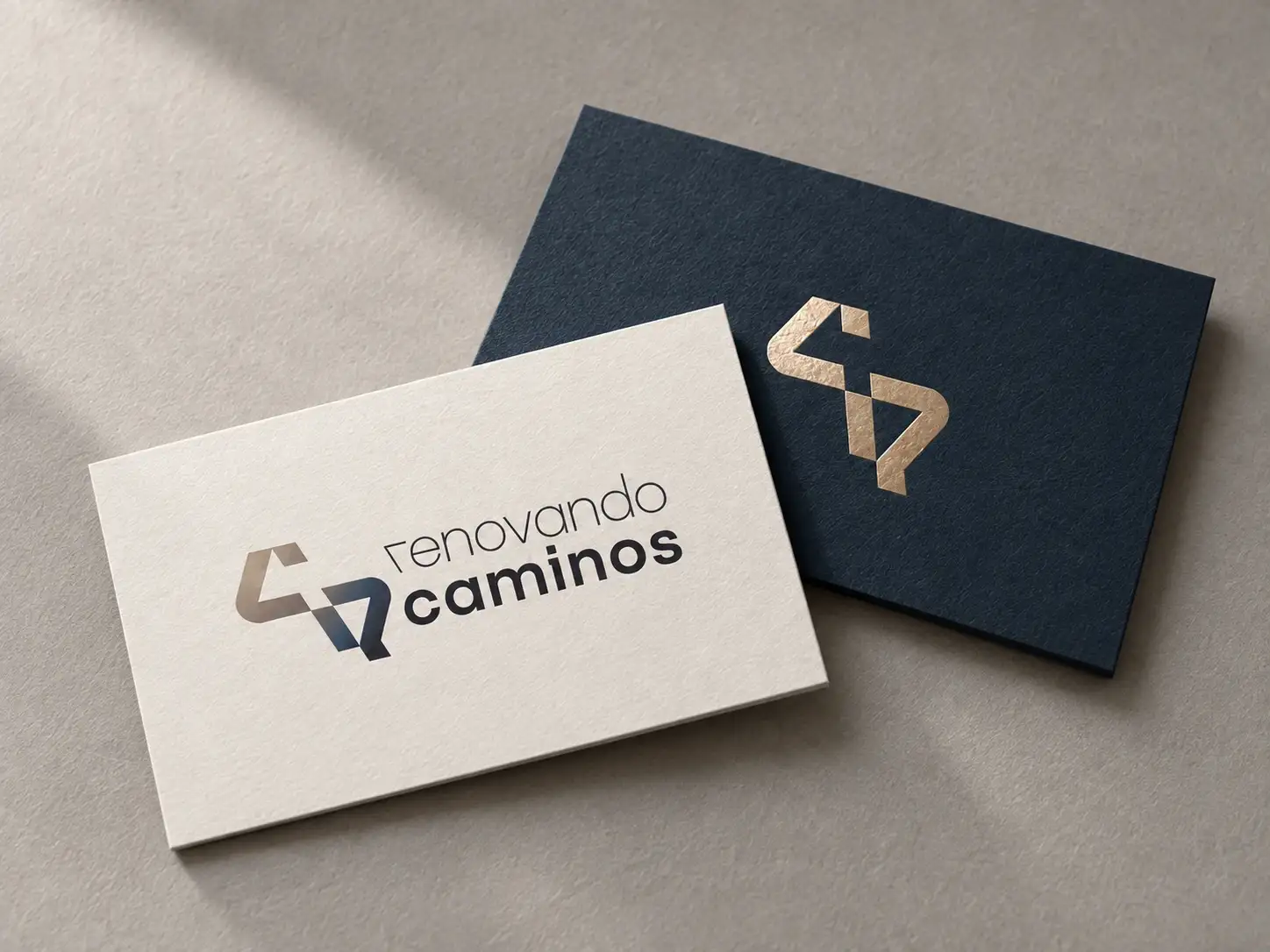 Tarjetas de visita de Renovando Caminos en crema y en azul noche con el símbolo en oro.